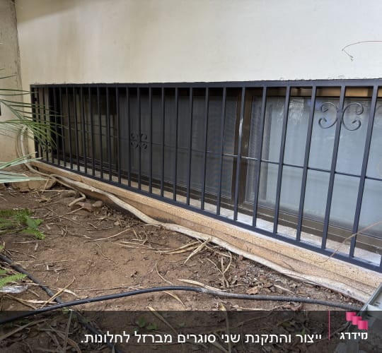 סורגי מתכת שחורים על חלון זכוכית מלבני